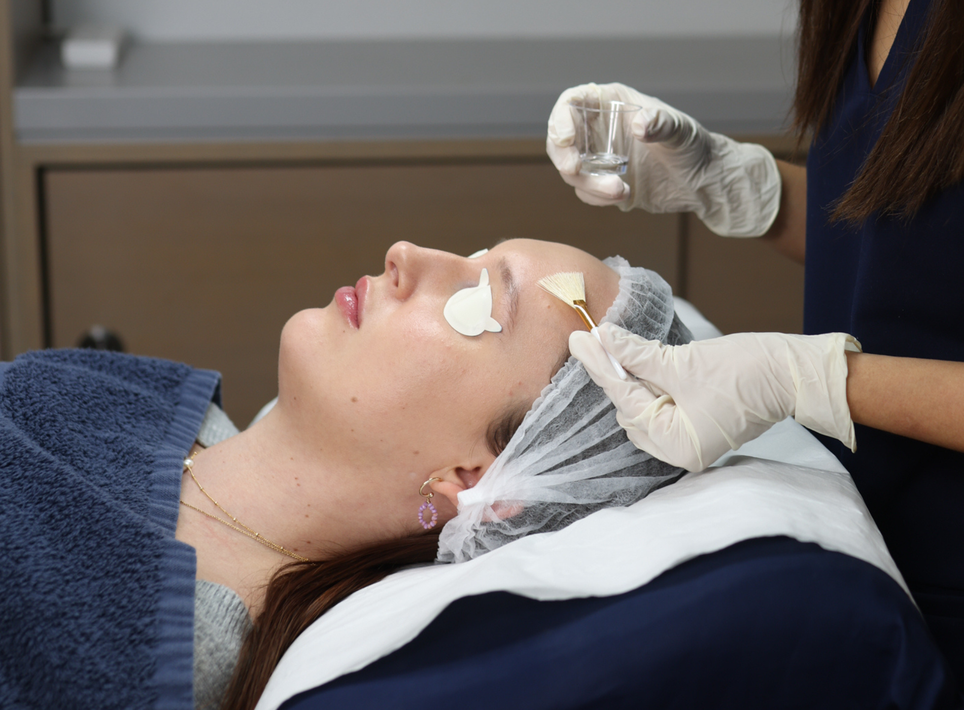 Woman lying on a bed under a blue towel getting a chemical peel treatment